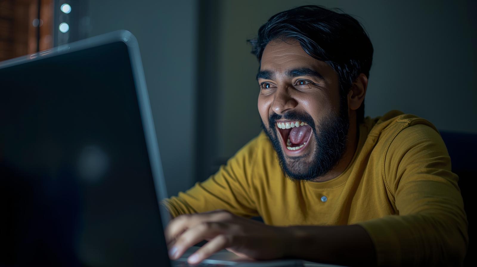 Happy man celebrating online casino win using laptop with blurred screen